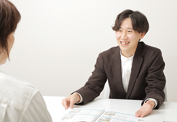 笑顔で資料を示しながら説明する営業スタッフ